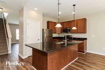 Dallas house for rent - A kitchen with a black counter top and wooden cabinets.