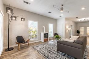 Cleveland apartment for rent - A living room with a grey couch, a chair, a floor lamp, and a fireplace.