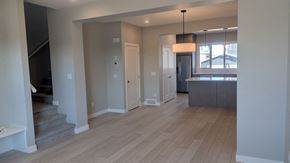 Chestermere house for rent - A spacious room with wooden flooring and a staircase on the left side.