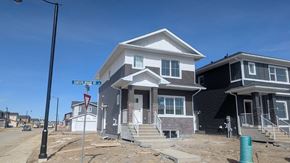 Chestermere house for rent - A house with a brown roof and white walls is in front of a street sign.