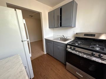 Washington apartment for rent - A kitchen with a white refrigerator, a stove, and grey cabinets.