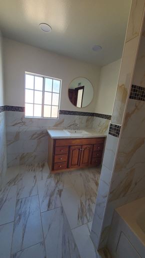 Carson house for rent - A bathroom with marble tiles and a wooden vanity.