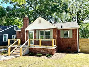 Greenville house for rent - A small brick house with a white roof and a wooden deck.
