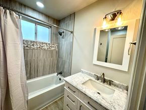 Greenville house for rent - A bathroom with a marble countertop and a white bathtub.