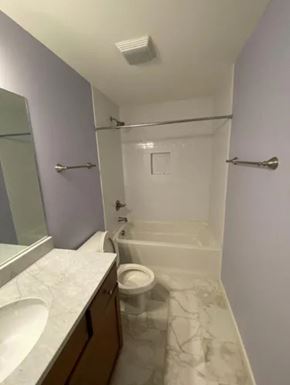 Nashville house for rent - A white toilet is in a bathroom with a white tub and sink.