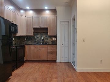 Calgary apartment for rent - A kitchen with wooden cabinets and a black microwave.