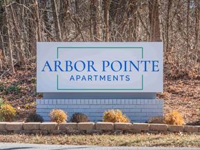 Winston-Salem apartment for rent - A sign for Arbor Pointe Apartments stands in front of a wooded area.