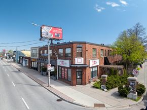 Toronto apartment for rent - A street view with a building on the right and a billboard on the left.