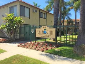 Buena Park apartment for rent - A sign for Calvonia Apartments is in front of a building with a green fence and trees.