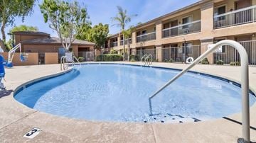 Tolleson apartment for rent - A swimming pool in front of a building with a blue sky in the background.