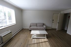 Denver apartment for rent - A living room with a couch, a coffee table, and a window with blinds.