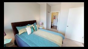 Lafayette apartment for rent - A bed with a blue and yellow comforter is in the foreground of a room.