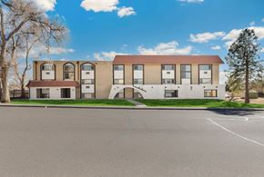 Lakewood apartment for rent - A building with a red roof and a parking lot in front.