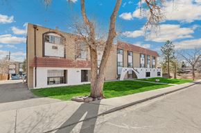 Lakewood apartment for rent - A tree stands in front of a two-story building with a white and brown facade.