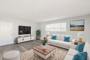 Lakewood apartment for rent - A living room with a white couch, a wooden coffee table, and a flat-screen TV on a cabinet.
