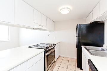 Craig apartment for rent - A black refrigerator sits in a kitchen with white cabinets and a white counter.