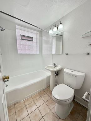 Denver apartment for rent - A white toilet sits next to a sink in a small bathroom.