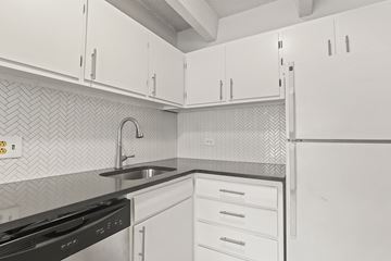 Denver apartment for rent - A kitchen with white cabinets and a black stove top oven.