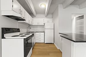 Denver apartment for rent - A modern kitchen with white cabinets and black countertops.