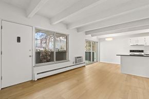 Denver apartment for rent - A white room with a wooden floor and a window with a view of trees outside.