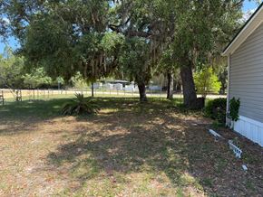Interlachen house for rent - A backyard with a white fence and a tree with Spanish moss hanging from it.