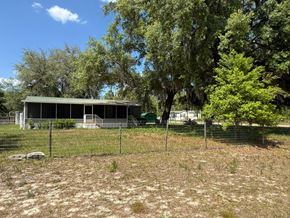 Interlachen house for rent - A house with a green roof is surrounded by trees and a fence.