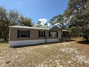 Palatka house for rent - A house with a metal roof and green shutters sits in a grassy field.