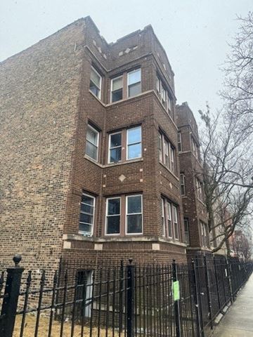 Chicago apartment for rent - A brick building with a black fence in front.