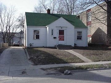 East Lansing house for rent - A white house with a green roof sits on a street corner.