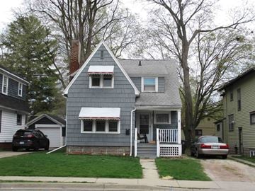 East Lansing house for rent - A grey house with a white roof and a red and white striped awning.
