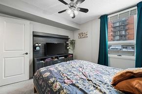 Calgary apartment for rent - A bedroom with a bed, a television, and a ceiling fan.