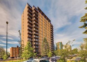 Calgary apartment for rent - A tall apartment building with a parking lot in front.