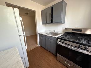 Washington apartment for rent - A kitchen with a white refrigerator, a stove, and grey cabinets.