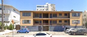 Los Angeles apartment for rent - A yellow and white building with a blue car parked in front.