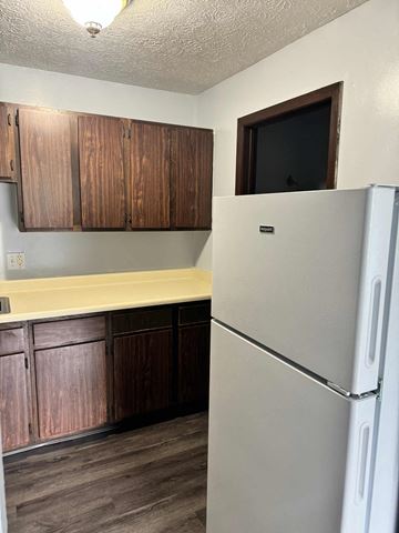 Scottdale apartment for rent - A white refrigerator stands in a kitchen with wooden cabinets.