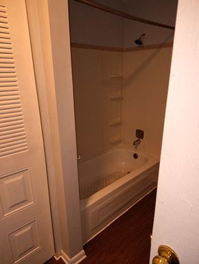 Scottdale apartment for rent - A white door with a gold handle is open to a bathroom with a white tub and shower.