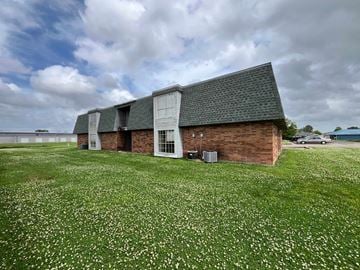 Thibodaux apartment for rent - A building with a green roof and a white door is surrounded by a field of white flowers.