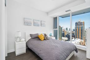 Calgary apartment for rent - A bedroom with a large bed and a view of the city.