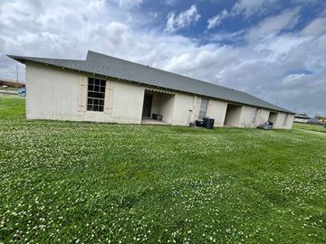Thibodaux apartment for rent - A large building with a grey roof and a grassy field in front of it.