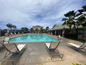 Kapolei apartment for rent - A pool with chairs around it and a building in the background.