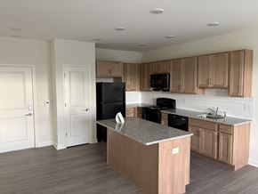 Newark apartment for rent - A kitchen with a black refrigerator, black stove, and wooden cabinets.
