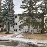 Edmonton apartment for rent - A white building with a brown fence in front of it.