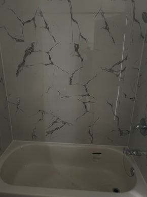 Edmonton apartment for rent - A white bathtub with a marble wall behind it.