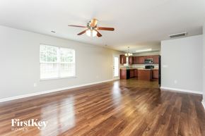 Whitsett house for rent - A spacious room with wooden floors and a ceiling fan.
