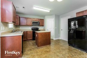 Whitsett house for rent - A kitchen with brown cabinets and a black refrigerator.