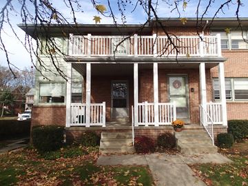 Shillington apartment for rent - A house with a white porch and a tree with leaves hanging over it.