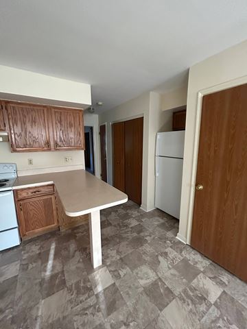 Shillington apartment for rent - A kitchen with a white table and brown cabinets.