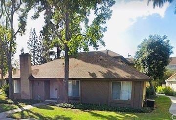 Placentia apartment for rent - A house with a brown roof and a chimney is surrounded by trees.