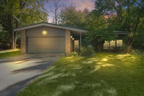 Belmont house for rent - A house with a garage is surrounded by trees and grass.