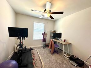 Greenville house for rent - A room with a fan, a TV, a desk, and a bicycle.